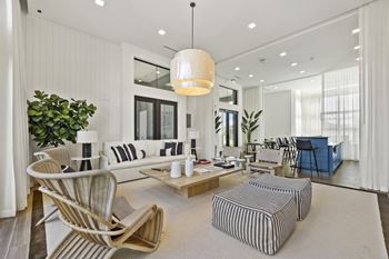 a living room with white walls and furniture and a large potted plant